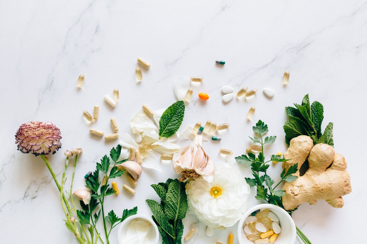 Natural herbs and pills arranged on a marble surface for a holistic healthcare theme.
